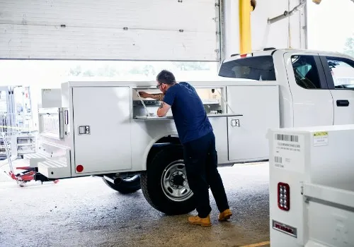 Technician working at a service truck tool compartment